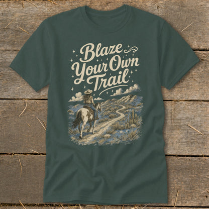 T-shirt graphic with text "Blaze Your Own Trail" and a person riding a horse on a desert path.