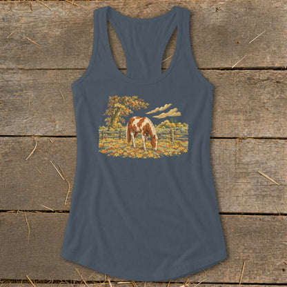 Horse grazing in a field of autumn leaves under a tree.