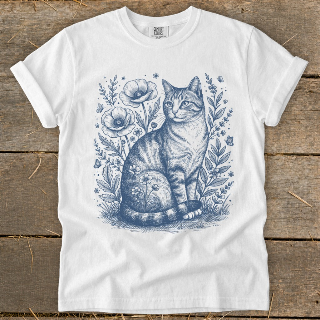 White t-shirt with a blue ink drawing of a tabby cat among wildflowers and butterflies.