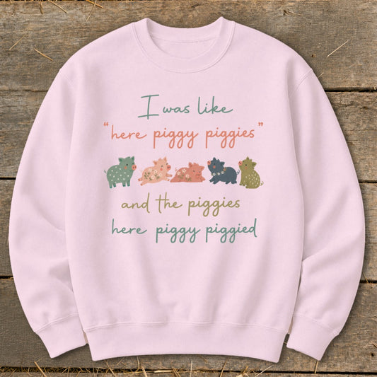 Pink sweatshirt with illustration of five pigs and text "I was like 'here piggy piggies' and the piggies here piggy piggied".