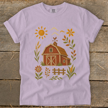 Lavender t-shirt with a charming farm scene featuring a red barn, sun, flowers, and corn.