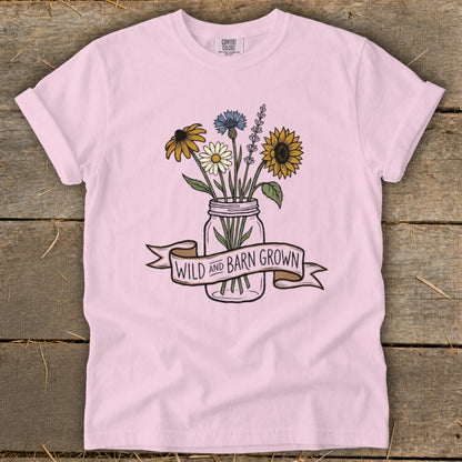 Pink t-shirt with a mason jar filled with wildflowers and text "WILD AND BARN GROWN".