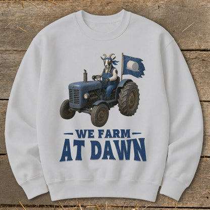 Goat in overalls driving a tractor with hay bale flag, text "We Farm At Dawn".
