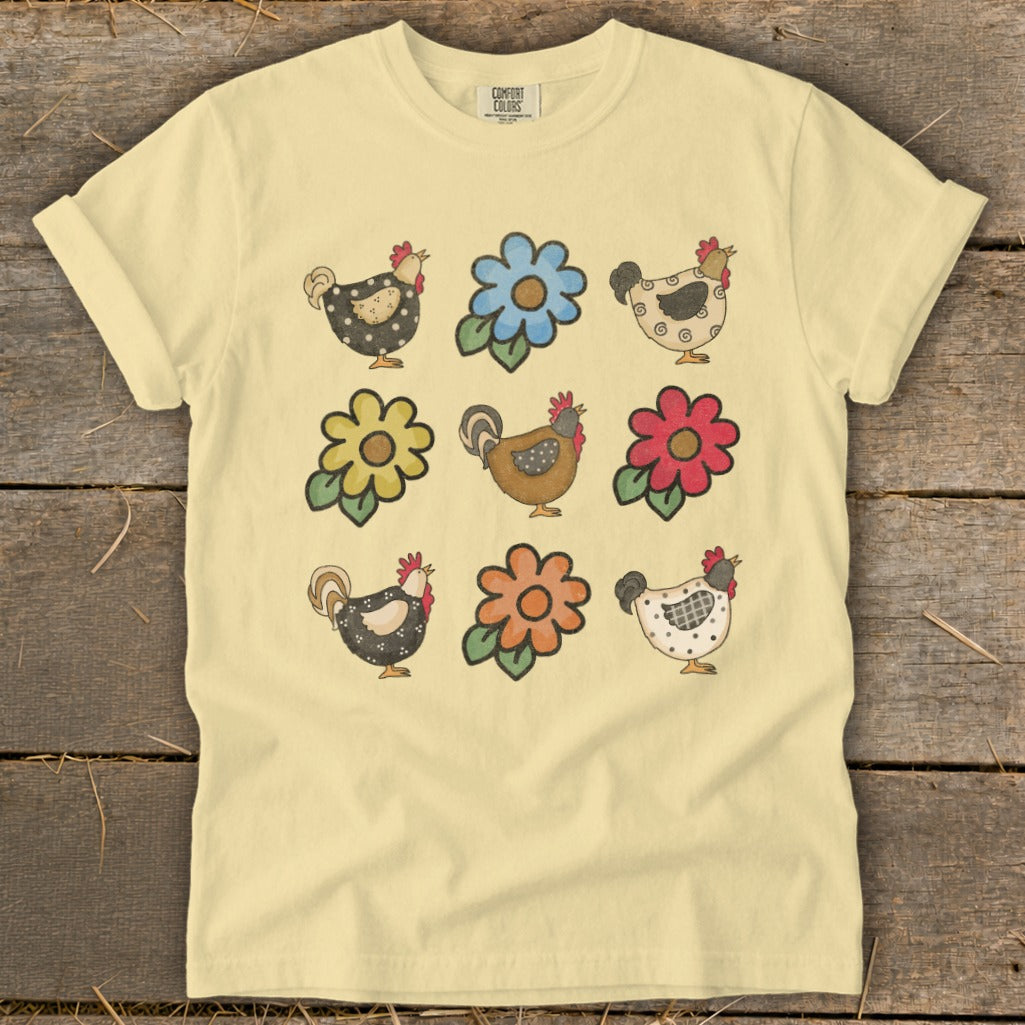 Light yellow t-shirt with a repeating pattern of stylized chickens and flowers.