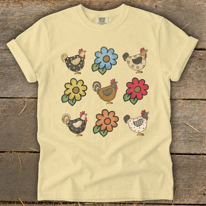 Light yellow t-shirt with a repeating pattern of stylized chickens and flowers.
