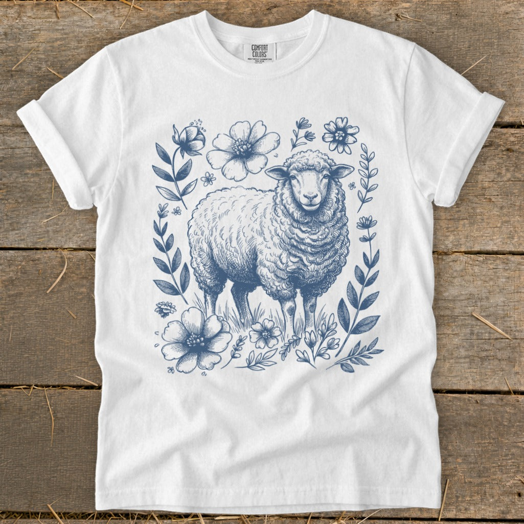 White t-shirt with a blue floral border and sheep illustration.