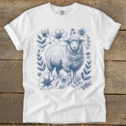 White t-shirt with a blue floral border and sheep illustration.