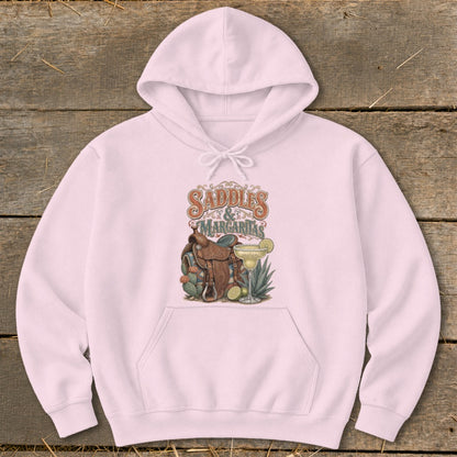 Pink hoodie with "Saddles & Margaritas" graphic featuring a saddle, margarita, and cacti.