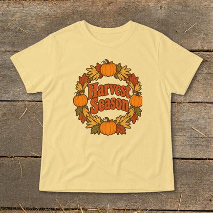 Yellow t-shirt with a circular design featuring pumpkins, leaves, and "Harvest Season" text.