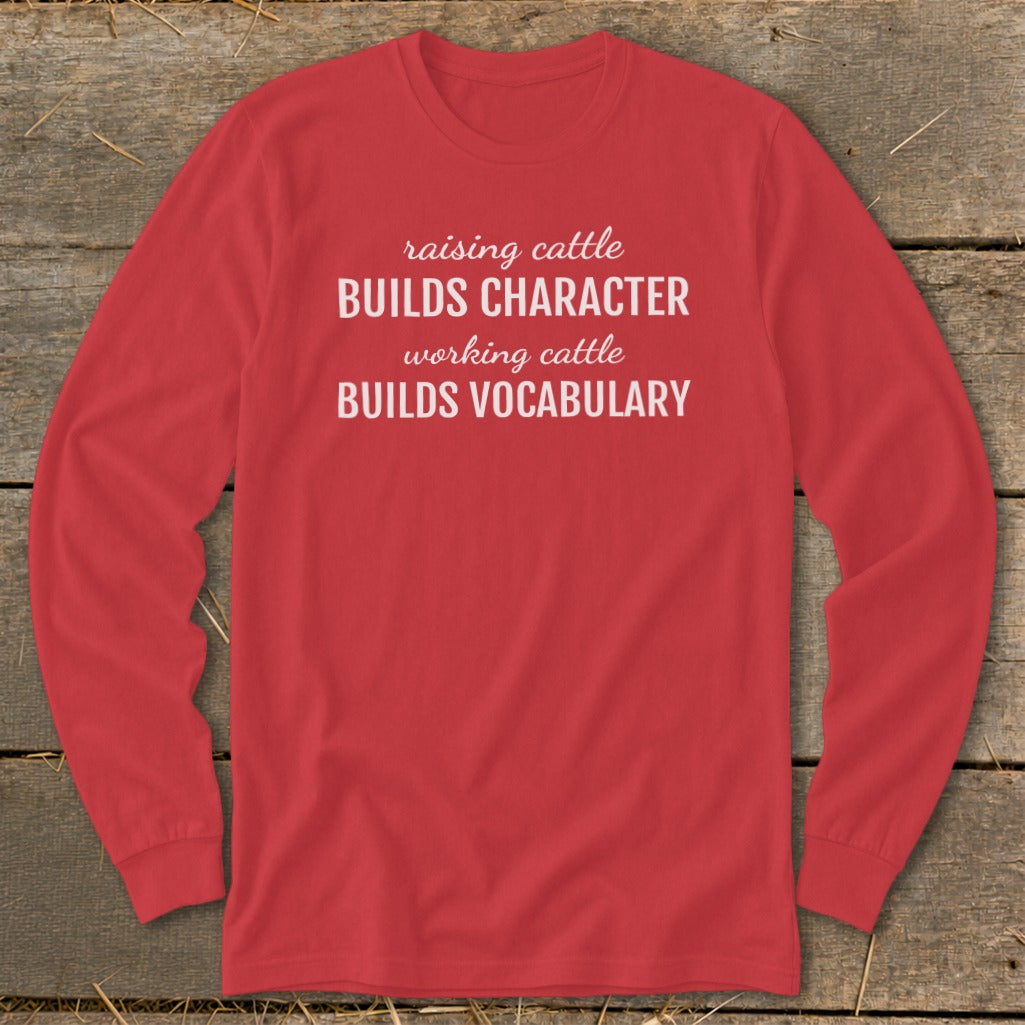 Red long-sleeve shirt with text: raising cattle BUILDS CHARACTER, working cattle BUILDS VOCABULARY.