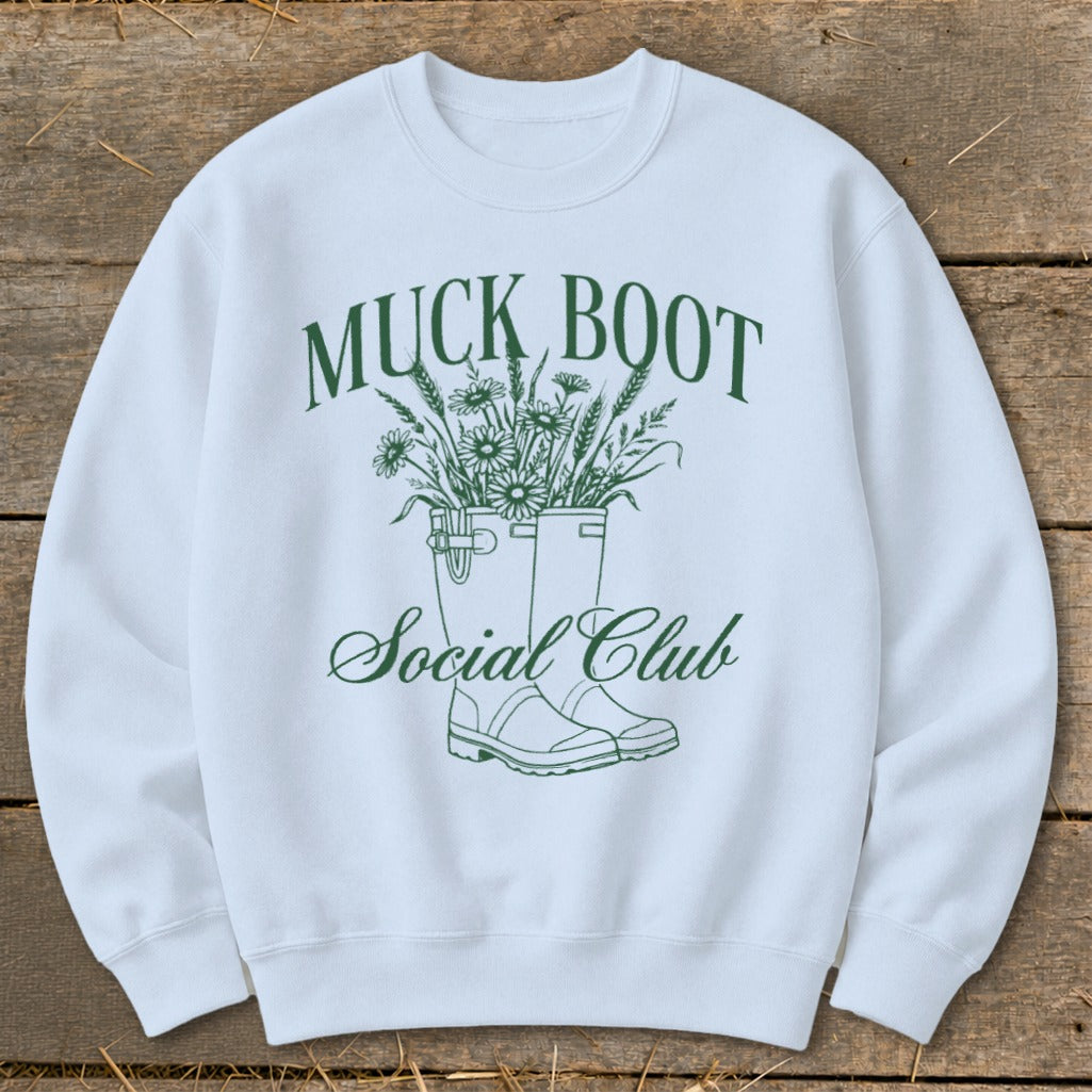 White sweatshirt with "Muck Boot Social Club" text and illustration of boots with flowers.