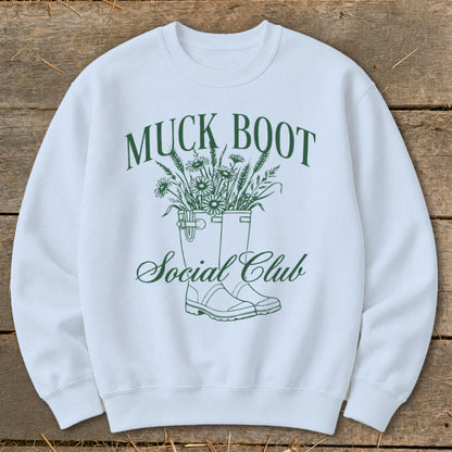 White sweatshirt with "Muck Boot Social Club" text and illustration of boots with flowers.