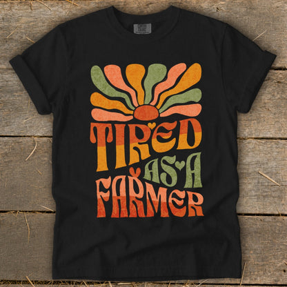 Black t-shirt with groovy "Tired As A Farmer" text and sun graphic.