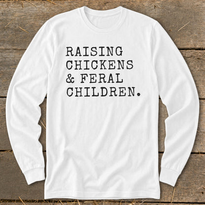 White long-sleeve shirt with black text: "Raising Chickens & Feral Children."