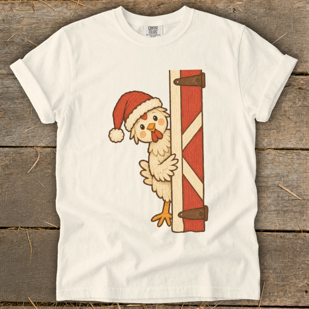 Cream t-shirt with a cartoon chicken wearing a Santa hat peeking from behind a barn door.