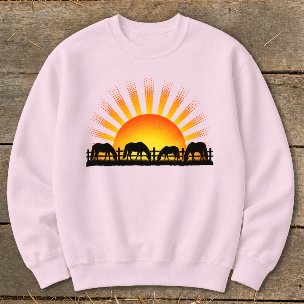 Pink sweatshirt with a sunset and four horses grazing behind a fence.