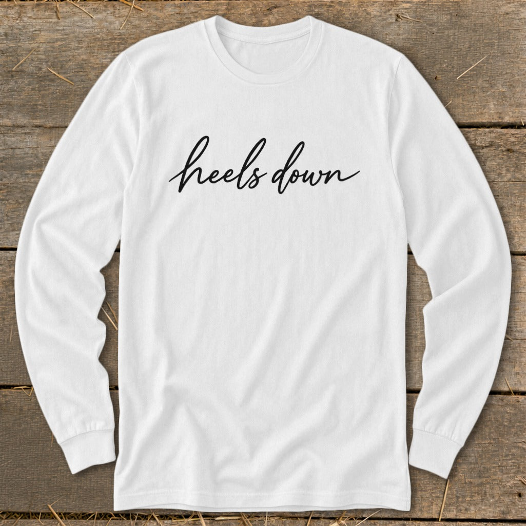 White long-sleeve shirt with "heels down" in black script text.