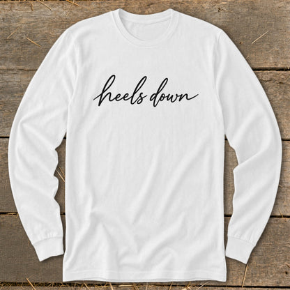 White long-sleeve shirt with "heels down" in black script text.