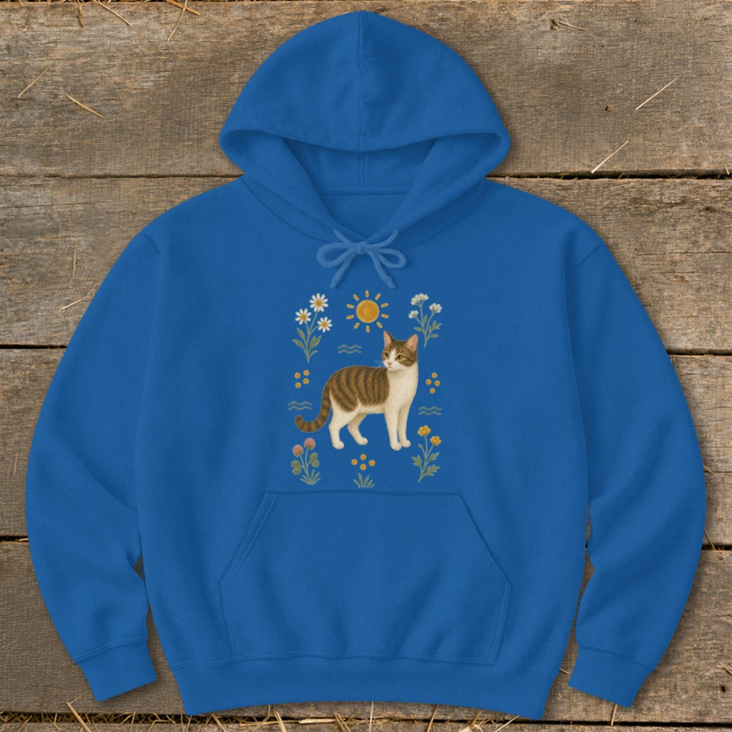 Blue hoodie with a brown and white cat surrounded by flowers and a sun.