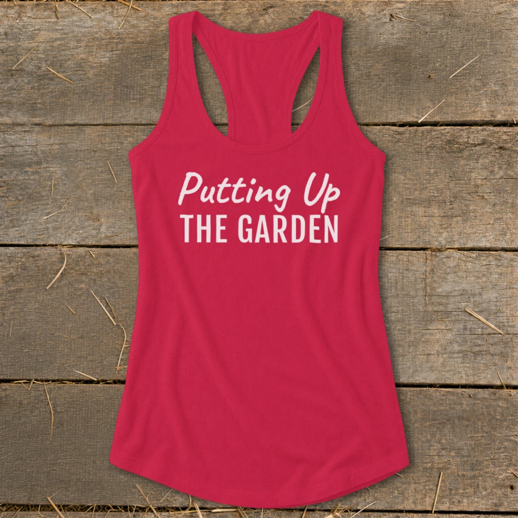 Pink racerback tank top with "Putting Up THE GARDEN" text.