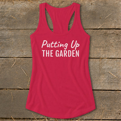 Pink racerback tank top with "Putting Up THE GARDEN" text.