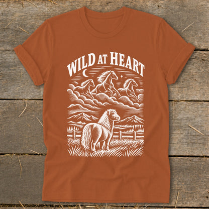 Orange t-shirt with white graphic of horses running and standing with text "Wild at Heart."