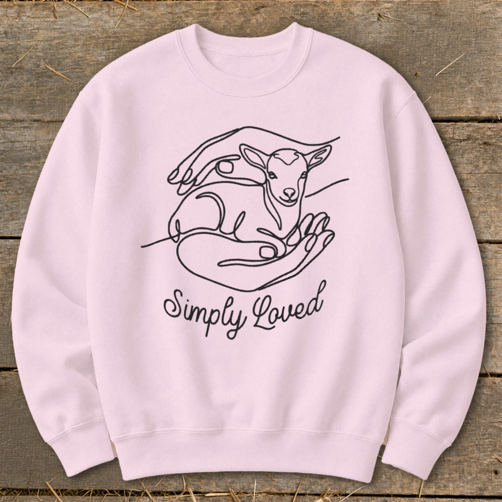 Pink sweatshirt with line art of hands holding a lamb and "Simply Loved" text.