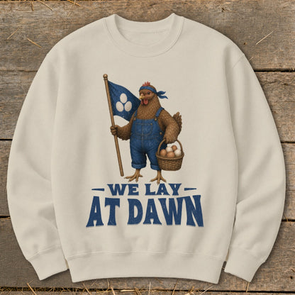 Cream sweatshirt with illustration of a chicken holding a flag and basket, text reads "We Lay At Dawn".
