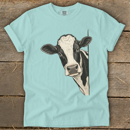 Light blue t-shirt with a black and white cow peeking from the right side.