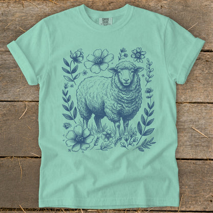 Aqua t-shirt with a navy blue illustration of a sheep surrounded by flowers and leaves.