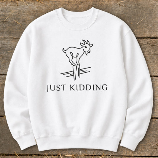 White sweatshirt with a line drawing of a goat standing on a post and the text "JUST KIDDING".