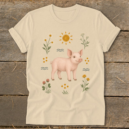 Cream t-shirt with a pink piglet illustration surrounded by flowers and the sun.