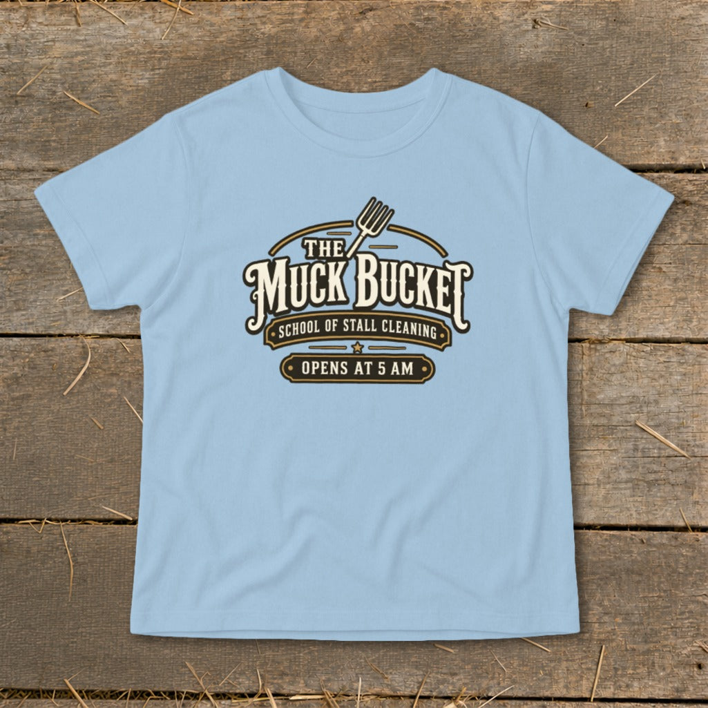 Light blue t-shirt with "The Muck Bucket School of Stall Cleaning Opens at 5 AM" logo.
