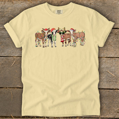 Group of five festive cows wearing Santa hats and Christmas lights.