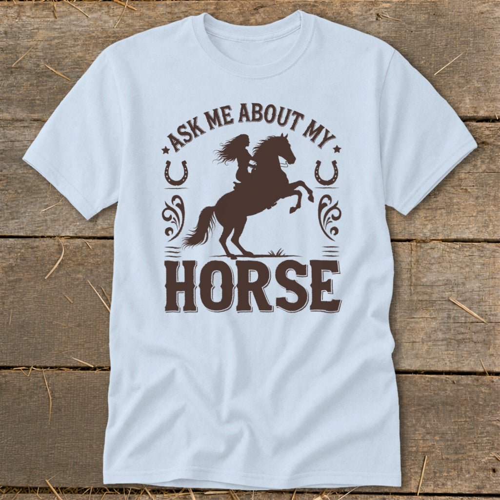 Light blue t-shirt with brown graphic of woman riding a horse and text "Ask Me About My Horse".