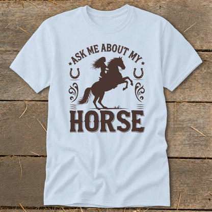 Light blue t-shirt with brown graphic of woman riding a horse and text "Ask Me About My Horse".