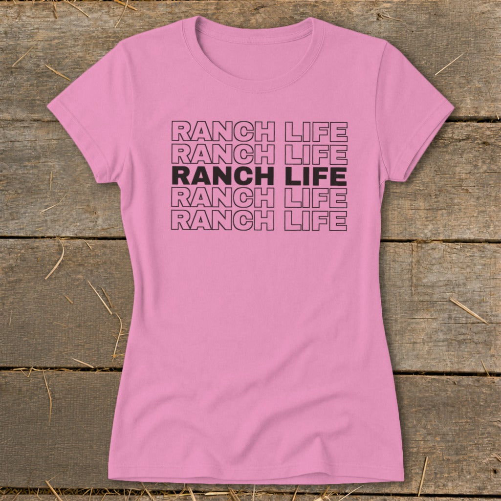 A short-sleeved pink t-shirt with five rows of stacked black text reading RANCH LIFE.