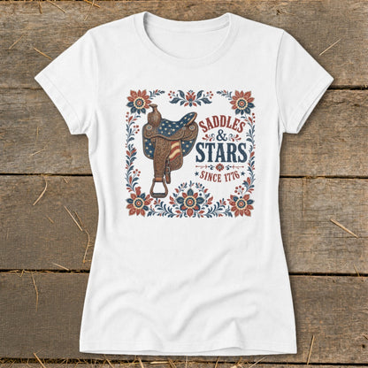 White t-shirt with "Saddles & Stars Since 1776" text and patriotic saddle graphic.