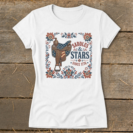 White t-shirt with "Saddles & Stars Since 1776" text and patriotic saddle graphic.