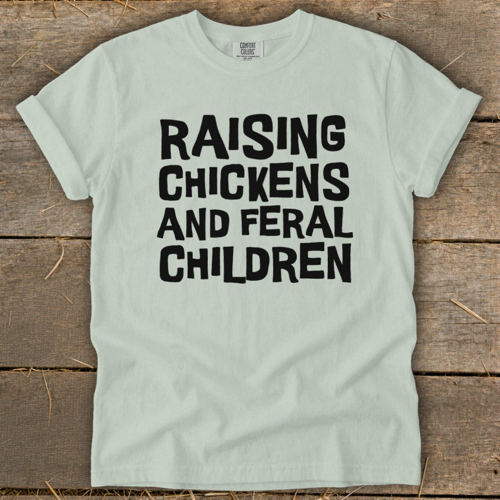 Light mint green t-shirt with black text reading "RAISING CHICKENS AND FERAL CHILDREN."