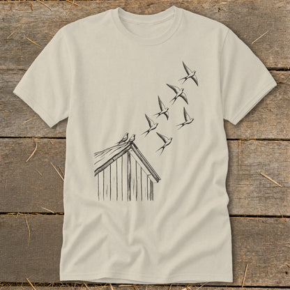 Light beige t-shirt featuring a line drawing of a small shed with birds flying upward from the roof.