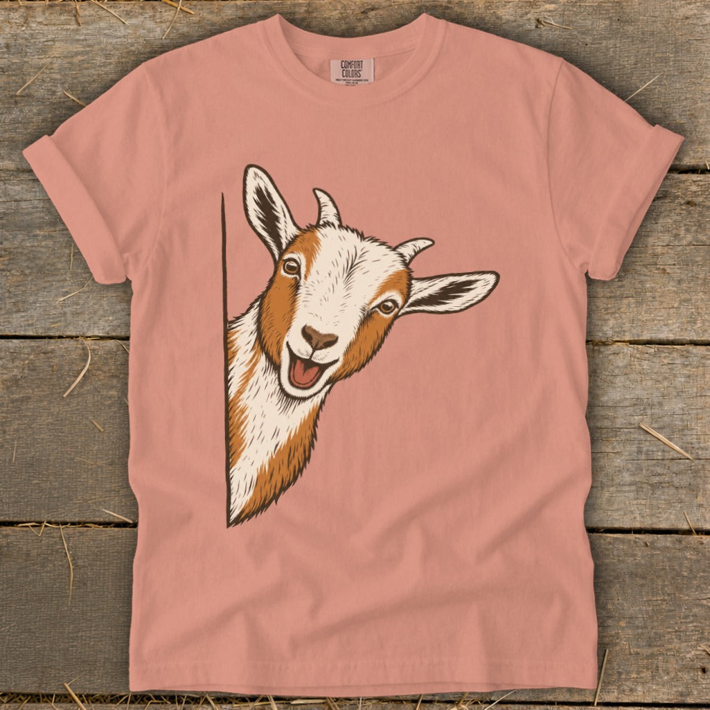 Peach t-shirt with a smiling goat peeking around the side.