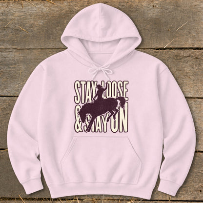 Pink hoodie with "Stay Loose & Stay On" text and bucking bronco silhouette.