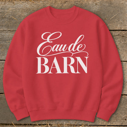 Red sweatshirt with white text "Eau de BARN" on a wooden background.