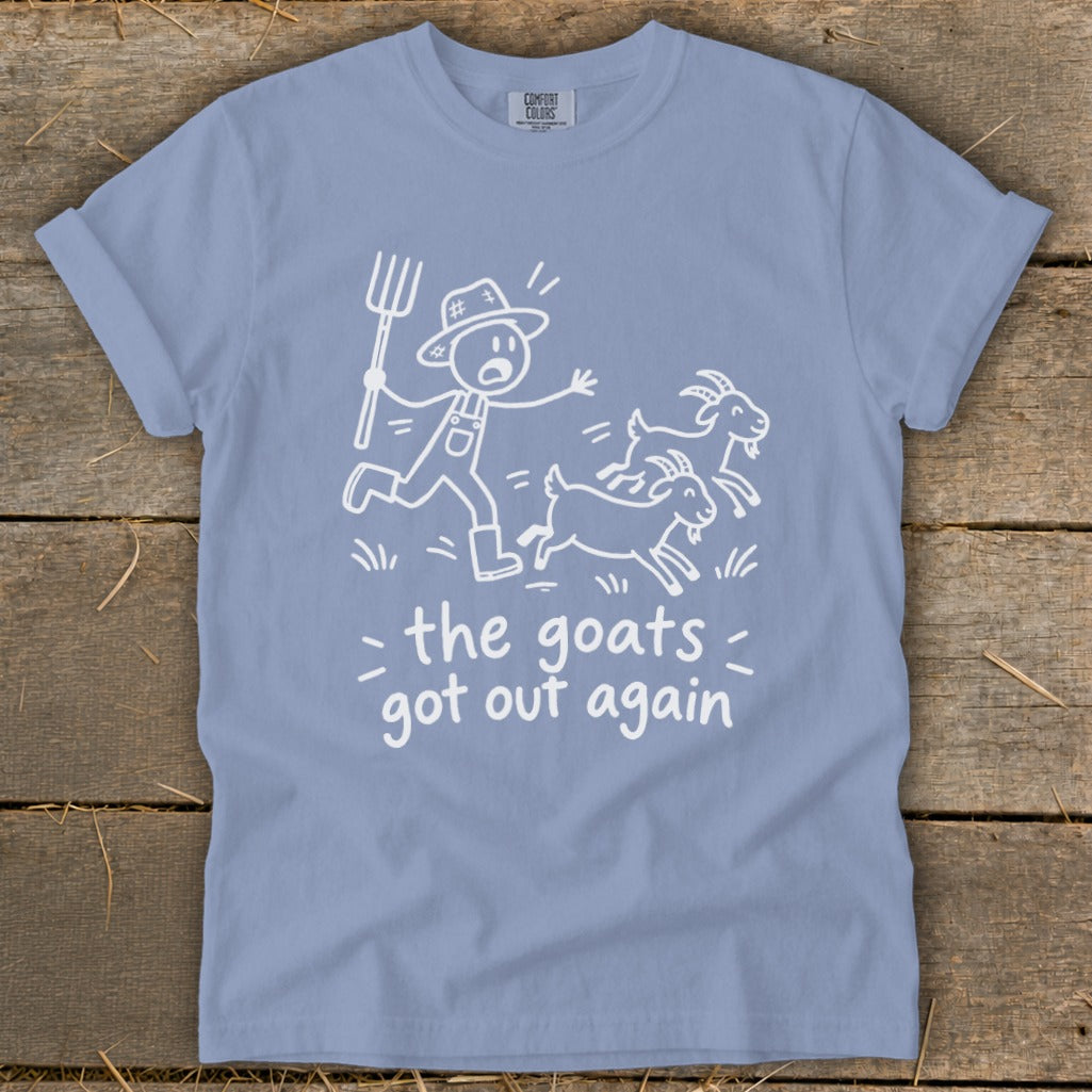 Blue t-shirt with white illustration of farmer chasing goats, text "the goats got out again".