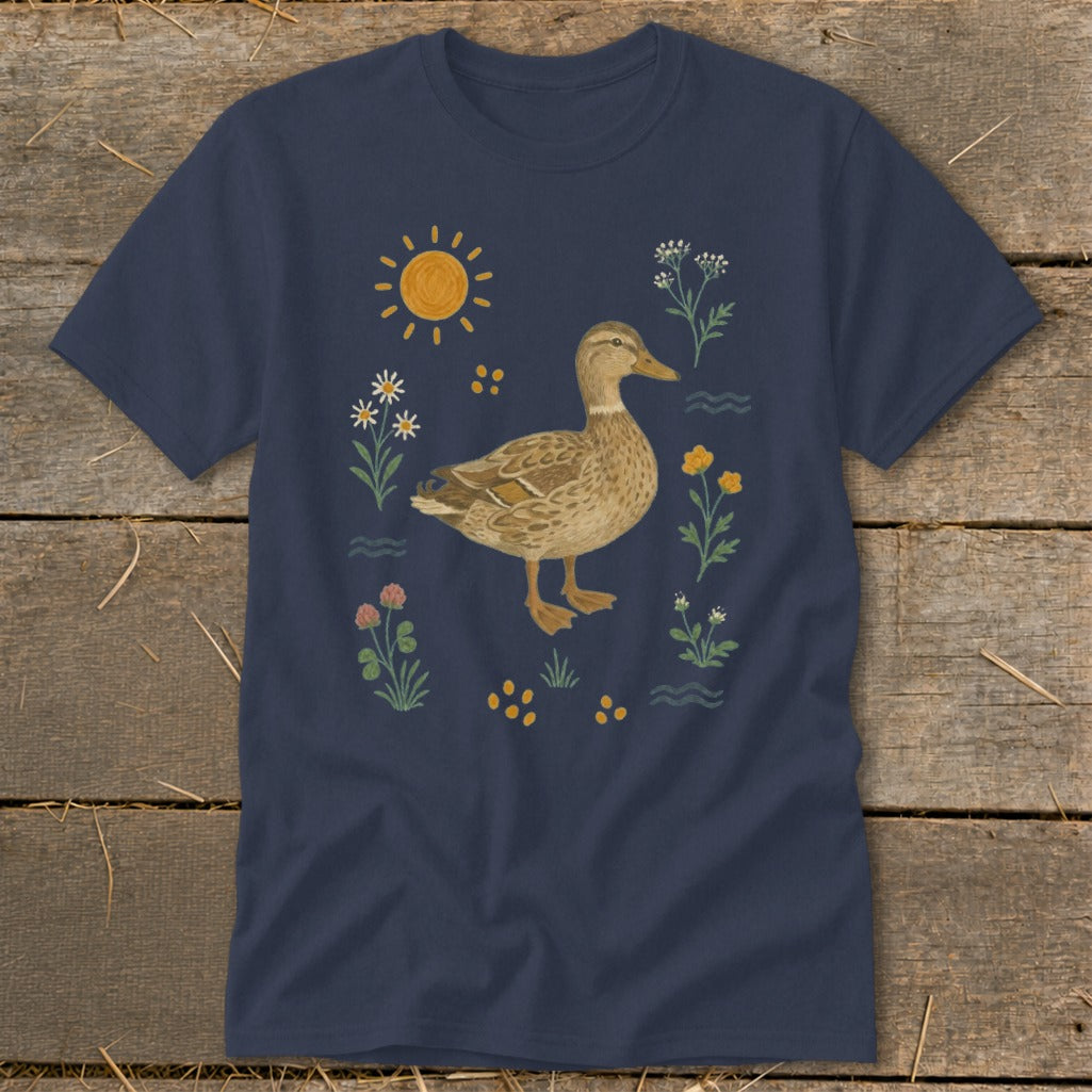 A brown duck stands surrounded by flowers, yellow dots, and a sun on a navy t-shirt.