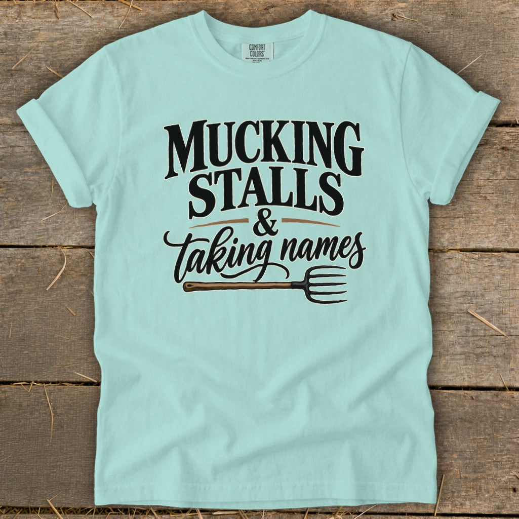 Light blue t-shirt with "Mucking Stalls & Taking Names" and a pitchfork graphic.