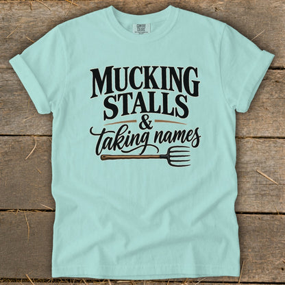 Light blue t-shirt with "Mucking Stalls & Taking Names" and a pitchfork graphic.