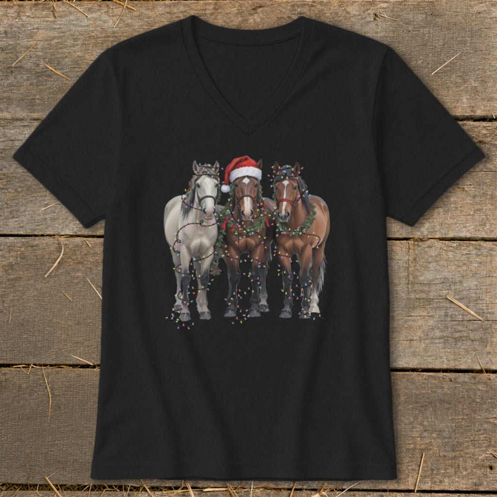 Three horses, one with a Santa hat, are decorated with Christmas lights and garland.