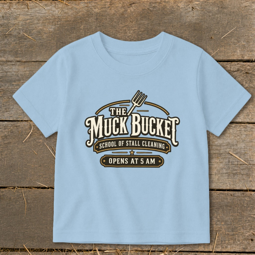 Light blue t-shirt with "The Muck Bucket School of Stall Cleaning Opens at 5 AM" graphic.
